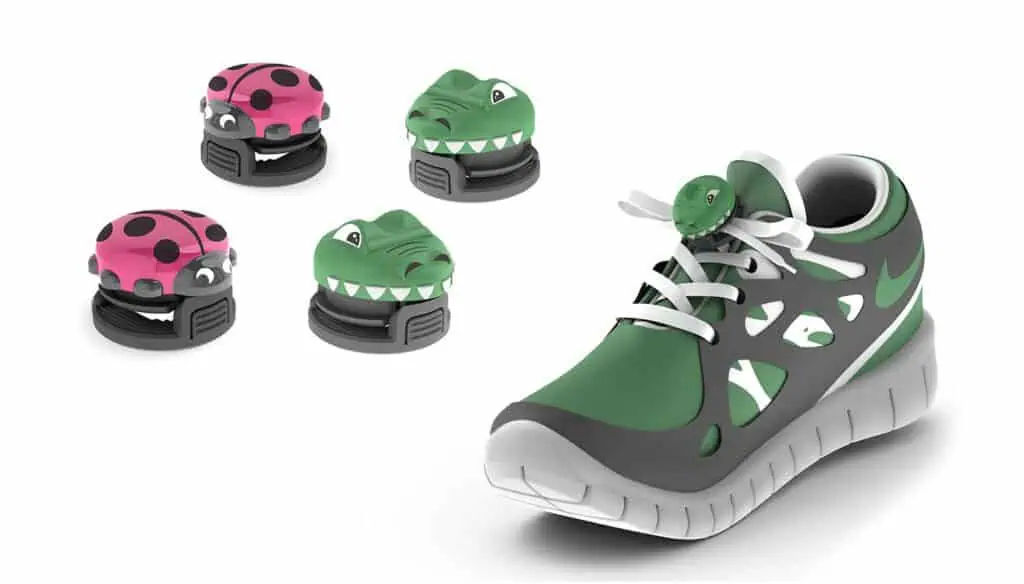 A green and gray sneaker with white laces is shown with small, colorful clips shaped like a ladybug and a crocodile. Additional ladybug and crocodile clips are displayed beside the shoe on a white background.