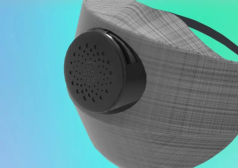 A close-up of a gray breathable face mask with a round black air filter labeled Go Prottex, shown against a blue and green gradient background.