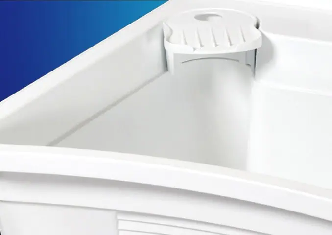 Close-up of a white plastic container with a rounded corner and a built-in soap or sponge holder, set against a blue gradient background.